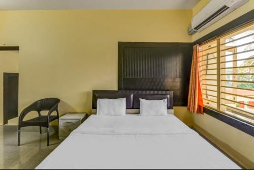een slaapkamer met een bed, een stoel en een raam bij Goroomgo Hotel Moon Chakra Tirtha Road Puri - Excellent Stay with Family, Parking Facilities in Puri