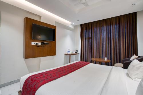a hotel room with a bed and a flat screen tv at Hotel Vilvah in Coimbatore