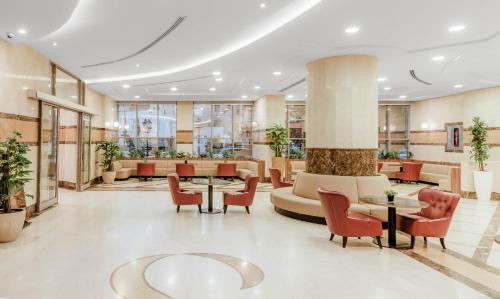 a lobby with a waiting area with chairs and tables at M Hotel Al Dana Makkah by Millennium in Mecca