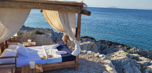 a bed on the side of a cliff near the ocean at Aponisos island in Megalochori