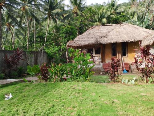 una pequeña cabaña con techo de hierba en un patio en MBE BALENG KU, en Mangsit