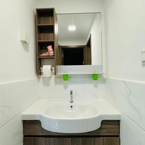 ein Badezimmer mit einem weißen Waschbecken und einem Spiegel in der Unterkunft Ataraxia 2B1R 4pax Condo Forest City 3A-3202 in Gelang Patah