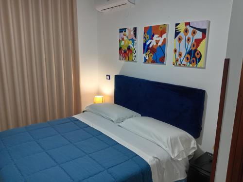 ein blau-weißes Bett in einem Zimmer mit Gemälden in der Unterkunft B&B villamariascauri in Scauri