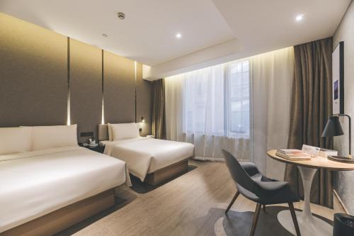 a hotel room with two beds and a table at Shanghai Atour Hotel On The Bund- People Square in Shanghai