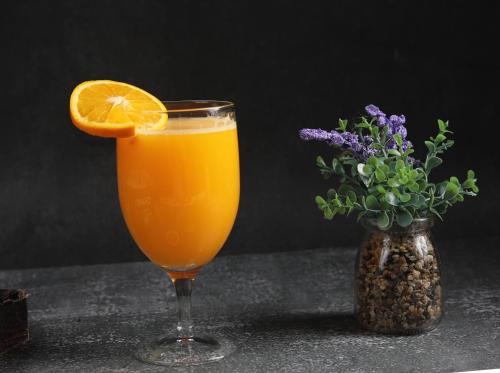a glass of orange juice next to a vase of flowers at Rosa Grand Hotel in Riyadh