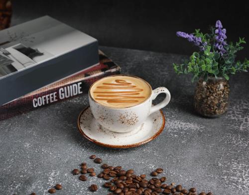 a cup of coffee sitting on a table with coffee beans at Rosa Grand Hotel in Riyadh