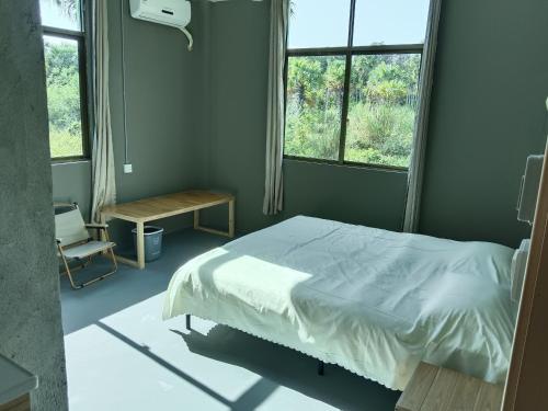 een slaapkamer met een bed en 2 ramen bij GAR'S Homestay in Wanning
