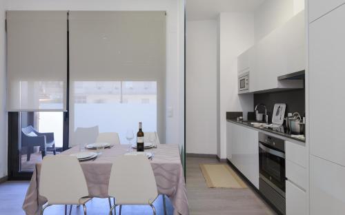 cocina blanca con mesa y sillas blancas en Apartamentos Lanceata, en A Revolta