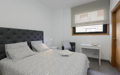 a bedroom with a bed and a desk and a window at Apartamentos Lanceata in Revolta