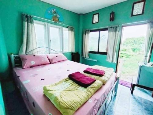 um quarto com uma cama com paredes verdes e janelas em หมอกอิงธาร รีสอร์ท เขาค้อ em Ban Khao Ya Nua