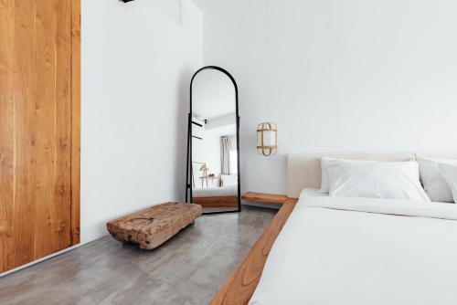 a bedroom with a white bed and a mirror at HOLA villas & lofts Uluwatu in Uluwatu