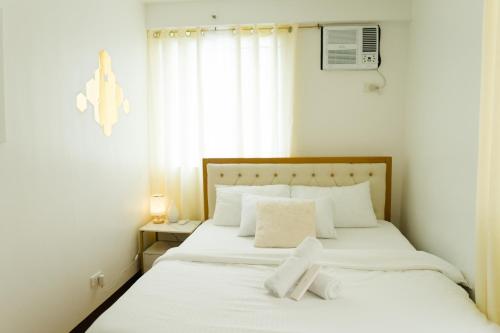a bedroom with a bed with white sheets and a window at Peaceful & quiet 1BR condo w/ pool access, TV&Wifi in Davao City
