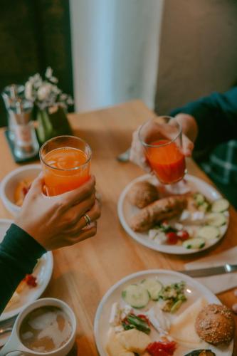 two people holding up glasses of juice at a table with food at Stadthotel Brunner in Schladming