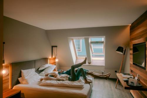 a person is laying on a bed in a room at Stadthotel Brunner in Schladming