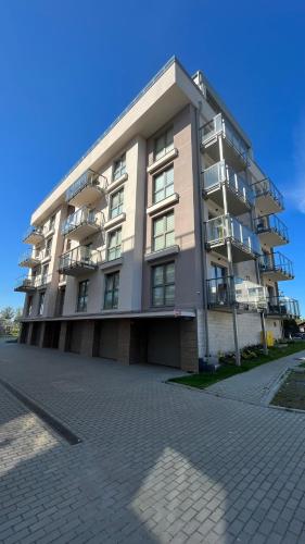 um grande edifício de apartamentos com varandas numa rua em Falla Apartamenty- ul Wiejska Ustronie Morskie em Ustronie Morskie