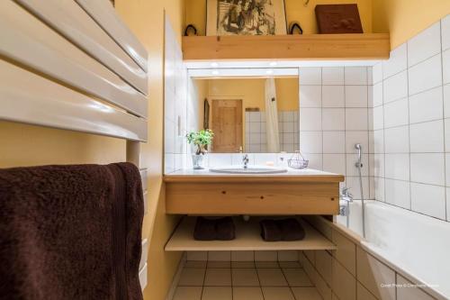 une salle de bains avec lavabo, miroir et baignoire dans l'établissement Ancolie 1er, à Val dʼIsère