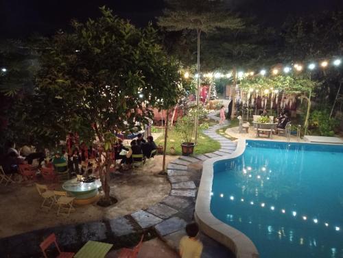 a swimming pool at night with people sitting at tables at Homestay Làng Tôi - Pleiku - Gia Lai in Plei Brêng