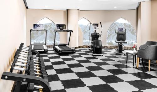 a gym with treadmills and ellipticals on a checkered floor at M Hotel Al Dana Makkah by Millennium in Mecca