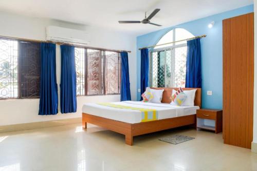 a bedroom with a bed with blue walls and windows at Goroomgo Elite Stay Bhubaneswar in Bhubaneshwar