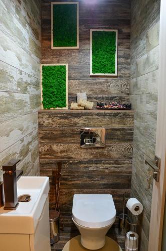 a bathroom with a white toilet and wooden walls at Апартамент Девио in Ruse