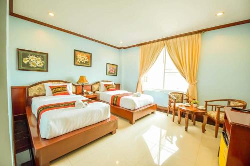 um quarto com 2 camas, uma secretária e uma janela em Soubundith Hotel em Pakse