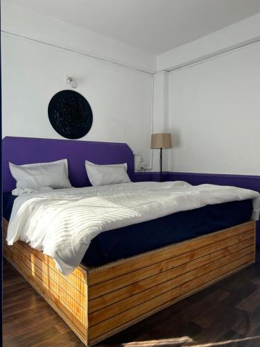 1 dormitorio con 1 cama grande y cabecero púrpura en Tiny Spot Hostel, en Manali