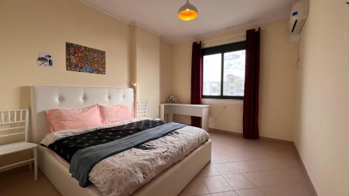 een slaapkamer met een bed met roze kussens en een raam bij Mikael Apartment in Durrës