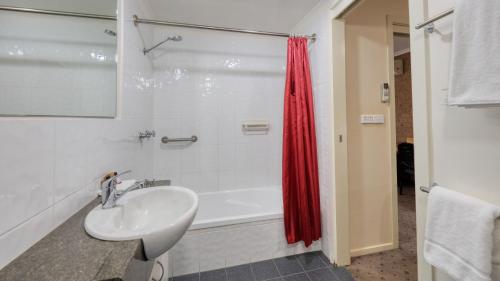 a bathroom with a sink and a bath tub at Ashton Motel in Tumut