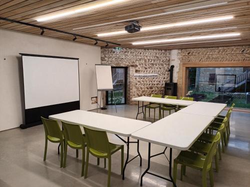 une salle de réunion avec des tables blanches et des chaises vertes dans l'établissement La ferme de Berlioz, à La Côte-Saint-André