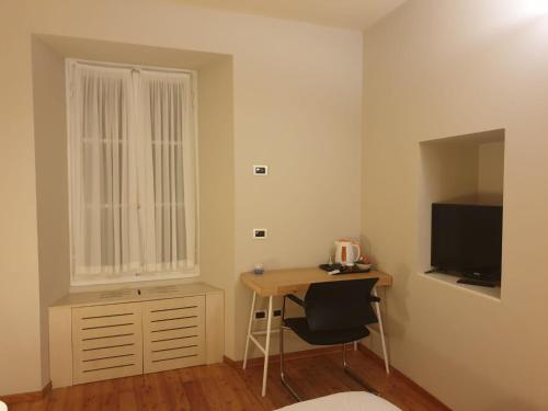Habitación pequeña con escritorio y TV. en Piccolo Hotel Olina en Orta San Giulio