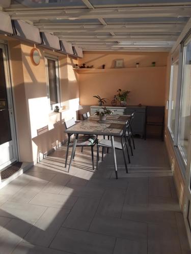 een kamer met een tafel en stoelen op een patio bij Chambres chez l habitant periode 6 juin 2024 in Bénouville