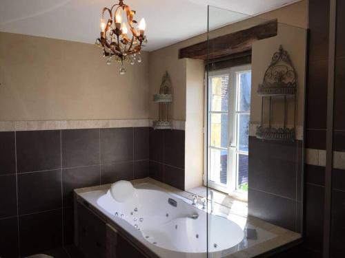 Maison de charme en Bourgogne في Coulanges-lès-Nevers: حمام كبير مع حوض استحمام ونافذة
