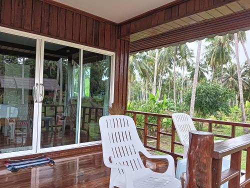 two white chairs on a porch with windows at Kohjum Freedom Resort in Ko Jum
