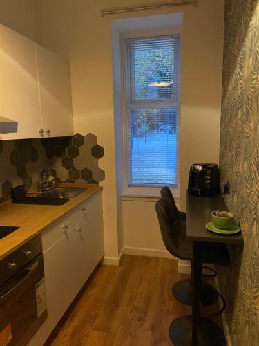uma pequena cozinha com uma mesa e uma janela em The Wee Studio Flat em Paisley