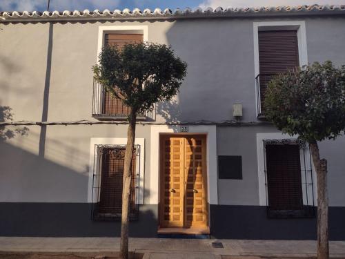 una casa blanca con una puerta y un árbol en Casa Rural con Estilo Valdepeñas, en Valdepeñas