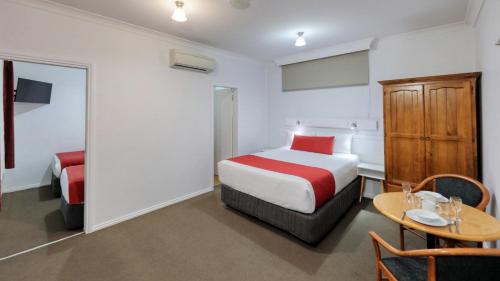 a hotel room with a bed and a table with a table at Ashton Motel in Tumut