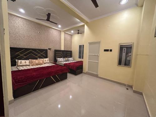 two beds in a large room with red sheets at TEMPLE TOWN HOMES assi ghat Varanasi in Varanasi