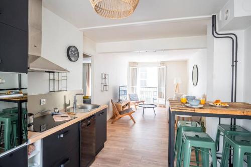 une cuisine avec une table et quelques tabourets verts dans l'établissement Au coin du Volcan - Hypercentre, au Havre