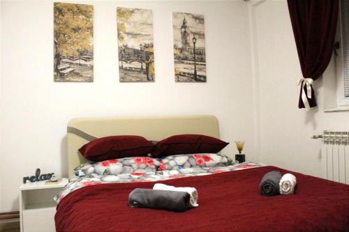 a bedroom with a bed with red sheets and pictures on the wall at Apartman 19 in Pale