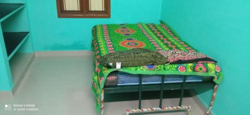 a bed with a colorful blanket on top of it at KEERTHISH NIVAS Home stay in Tiruvannāmalai