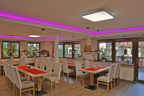 ein Esszimmer mit Tischen, Stühlen und rosafarbener Beleuchtung in der Unterkunft Gasthof Pension Alpenblick in Radfeld
