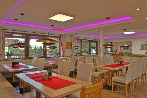 a restaurant with tables and chairs and pink lighting at Gasthof Pension Alpenblick in Radfeld