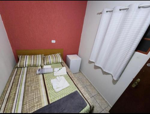 een kleine slaapkamer met 2 aparte bedden en een raam bij Quarto Guararema 2 in Guararema