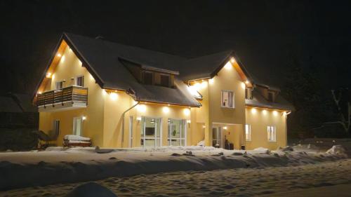 a house with lights on it in the snow at Zajazd Stronie in Stronie Śląskie