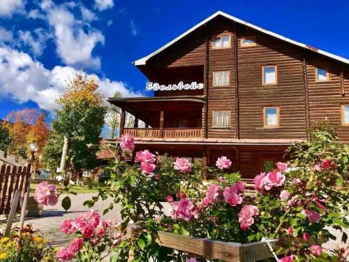 a wooden house with flowers in front of it at Едельвейс-Будапешт in Yasinya