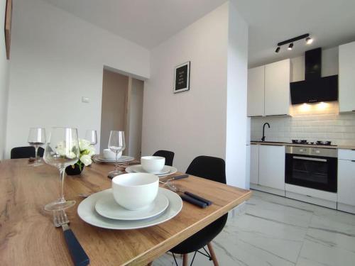 a kitchen with a wooden table with plates and wine glasses at ***Santorini Apartament*** - 40m² ✓ in Rybnik