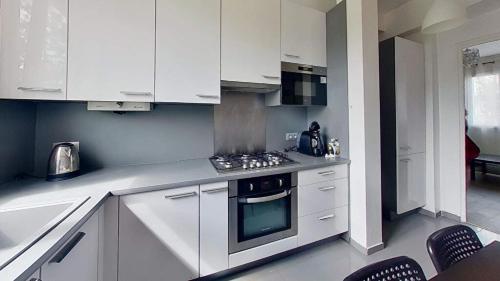 une cuisine avec des armoires blanches et un four à plaques de cuisson dans l'établissement Superbe appartement à La Garenne Colombes, à La Garenne-Colombes