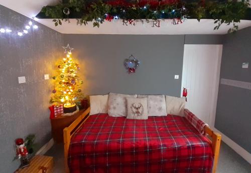 a bedroom with a bed and a christmas tree at Ramblers Rest in Meopham