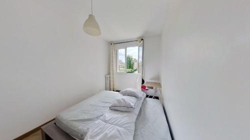 - une petite chambre avec un lit dans un mur blanc dans l'établissement Superbe appartement à La Garenne Colombes, à La Garenne-Colombes