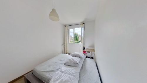 ein kleines Schlafzimmer mit einem Bett in einer weißen Wand in der Unterkunft Superbe appartement à La Garenne Colombes in La Garenne-Colombes